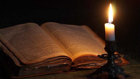 Ein antikes Buch mit einer Brille und einer Kerze. © fotolia.com Foto: Alexander Zlatnikov