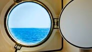 Blick auf ein Meer durch ein Bullauge einer Schiffskabine. © picture alliance / Bildagentur-online/Tetra Images | Bildagentur-online/Tetra Images 