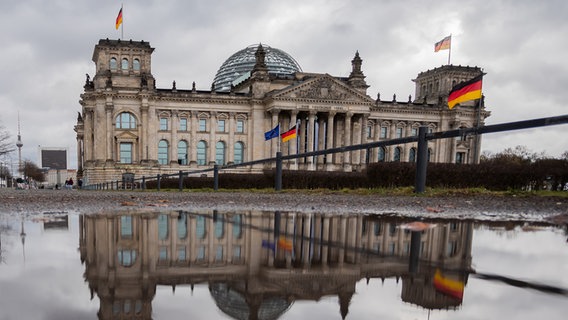Das Reichstagsgebäude spiegelt sich am Morgen in einer Pfütze © picture alliance Foto: Christoph Soeder
