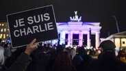 Eine Person hält vor dem Brandenburger Tor "Je suis Charlie"-Schild hoch ©  picture alliance / BREUEL-BILD 