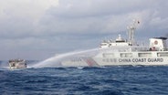 Ein Schiff der chinesischen Küstenwache Wasserwerfer schießt auf das von der philippinischen Marine betriebene Versorgungsschiff «Kalayaan» (r), als es sich der Second-Thomas-Untiefe im umkämpften südchinesischen Meer nähert. © picture alliance/dpa/PHILIPPINE COAST GUARD/AP | Uncredited Foto: picture alliance/dpa/PHILIPPINE COAST GUARD/AP | Uncredited
