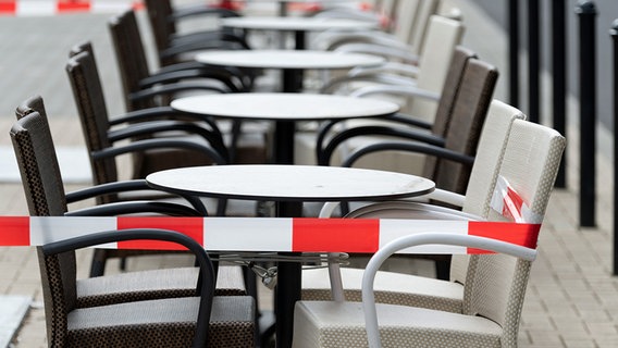 Eine Reihe von Tischen und Stühlen, die mit Absperrband abgesperrt sind. © dpa Bildfunk 