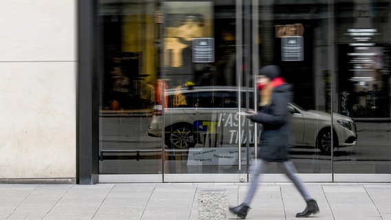 Eine Frau geht vor einem geschlossenen Geschäft entlang. © picture alliance Foto:  Axel Heimken dpa