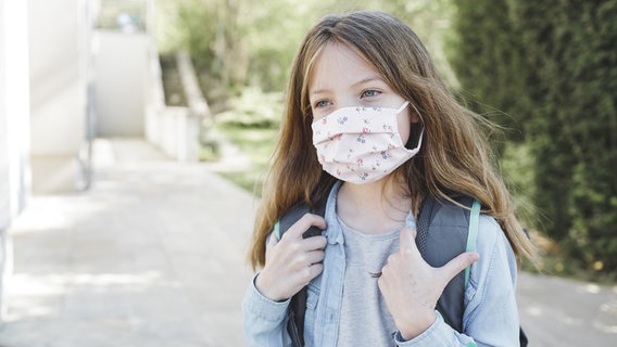 Ein Mädchen mit Schulranzen und Schutzmaske auf dem Schulweg. © panthermedia Foto: Hannes_Eichinger