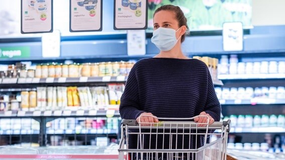 A woman wearing a protective mask in the supermarket.  © picture alliance Photo: Kirsten Nijhof