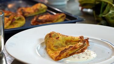 Crespelle with spinach, ham and mozzarella and some sauce served on a plate.  © NDR Photo: Florian Kruck