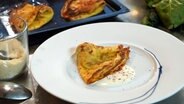 Crespelle mit Spinat, Schinken und Mozzarella und etwas Soße auf einem Teller angerichtet. © NDR Foto: Florian Kruck