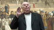 Dario Fo winkt vor einem alten Gemälde. © Imago Foto: Italy Foto Press