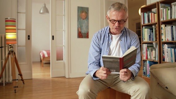 Ein Mann liest aus einem Buch vor. © NDR 