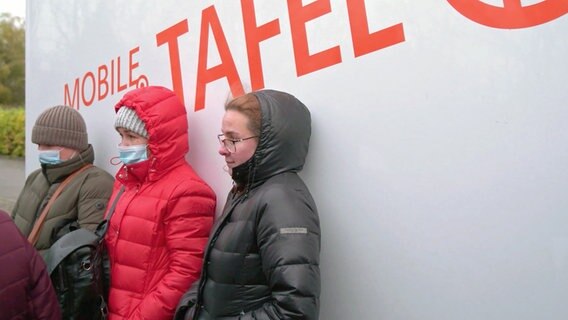 Drei Frauen stehen in Wintermänteln vor einem Bus mit der Aufschrift "Mobile Tafel". © NDR 