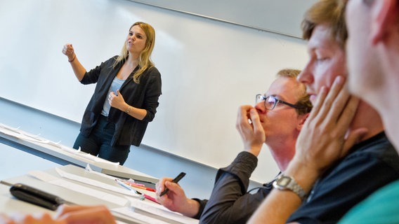 Eine Frau hält stehend eine Rede, drei Männer hören ihr zu. © picture alliance / dpa Foto: Franziska Gabbert