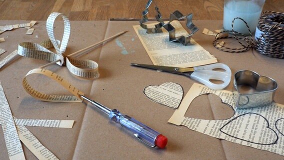 Material für das Basteln mit Buchseiten liegt auf einem Tisch. © NDR Foto: Anja Deuble