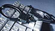 Handschellen auf Computertastatur © Fotolia.com Foto: Spuno