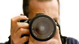 Ein Fotograf mit einer digitalen Spiegelreflexkamera © picture alliance / dpa Themendienst 