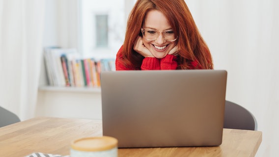 Eine rothaarige Frau blickt lächelnd in einen Laptop © Getty Images / iStockphoto Foto: contrastwerkstatt