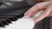Ein paar Finger schlagen Tasten auf dem Klavier an, nur diese sind scharf zu erkennen, der Rest des Klaviatur liegt unscharf im Hintergrund. © NDR 