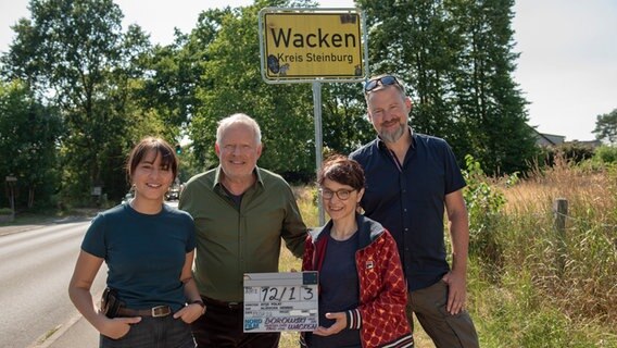 Drehstartfoto vor dem Ortsschild von Wacken mit v.l.n.r.: Almila Bagriacik, Axel Milberg, Ayse Polat (Regie) Aljoscha Hennig (Kamera) © NDR/Thorsten Jander Foto: Thorsten Jander