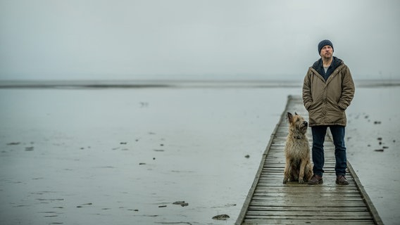Sörensen (Bjarne Mädel) steht mit seinem Hund auf einem Steg. © NDR/Michael Ihle Foto: Michael Ihle