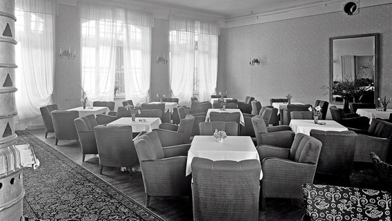 Ein Raum mit Tischen und Clubsesseln in einem Hotel  