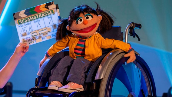 Elin, der neue Charkerter in der Sesamstraße. Ein selbstwußtes Mädchen mit schwarzen Zöpfen. Es nutzt einen Rollstuhl. © NDR/Thorsten Jander Foto: Thorsten Jander