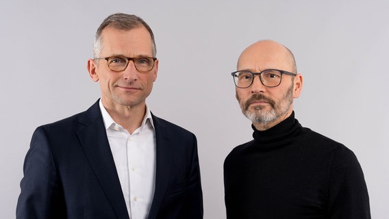 Dr. Michael Kühn und Steffen Klusmann stehen vor einer weißen Fotowand und schauen in die Kamera. © NDR/Janis Röhlig Foto: Janis Röhlig
