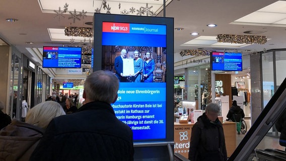NDR Nachrichten werden auf  Bildschirm im Einkaufszentrum gezeigt.  