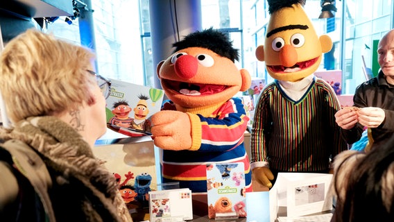Präsentation der Sesamstraßen-Briefmarke: Ernie und Bert als lebensgroße Figuren verteilen die neuen Post- und Paketprodukte an Besucher*innen. © NDR/Jann Wilken Foto: Jann Wilken
