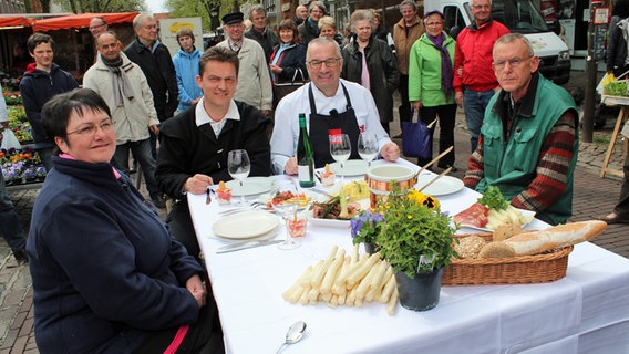 Rainer Sass am Tisch mit den Markthändlern. © dmfilm und tv produktion GmbH & Co. KG 