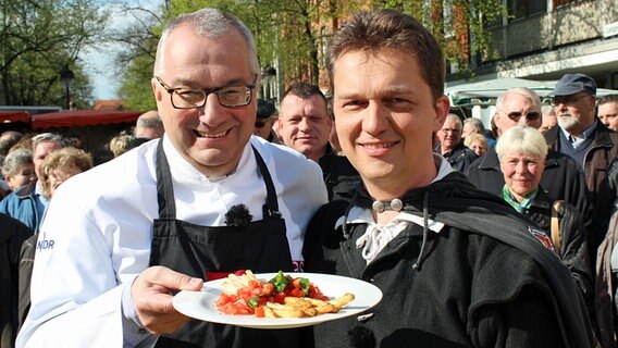 Rainer Sass mit dem Nienburger Nachtwächter Stefan Hilker und einem Spargelgericht © dmfilm und tv produktion GmbH & Co. KG 