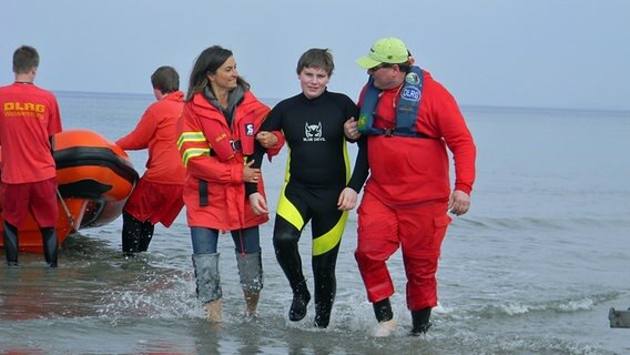 Inka Schneider und ein DLRG-Mitarbeiter führen einen 'Geretteten' aus dem Wasser © NDR 