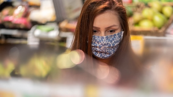 Eine Frau mit Mundschutz kauft in einem Supermarkt Gemüse ein. © picture alliance Foto: Robert Michael