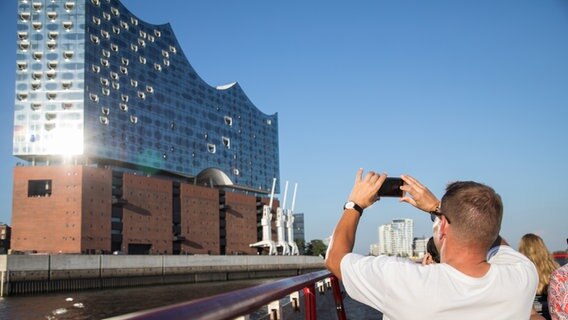 Touristen fotografieren am 17.07.2018 in Hamburg von einer Fähre aus die Elbphilharmonie. © picture alliance / dpa Foto: Christin Klose