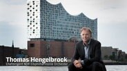 Thomas Hengelbrock sitzt vor der Elbphilharmonie © NDR 
