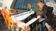 Menschen verbrennen Geldscheine vor der Elbphilharmonie © NDR 
