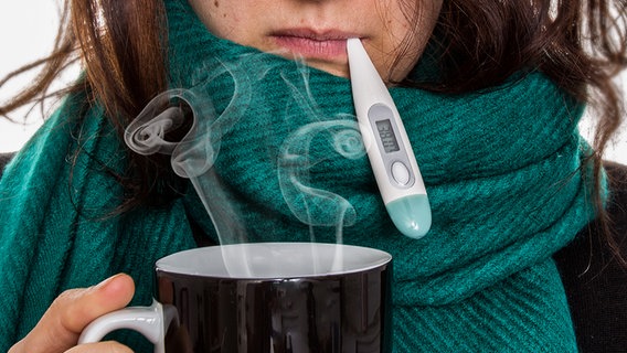 Erkältete Frau mit dampfenden Tee und Thermometer im Mund. © fotolia Foto: Fabian Faber