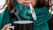 Erkältete Frau mit dampfenden Tee und Thermometer im Mund. © fotolia Foto: Fabian Faber