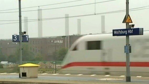 Ein ICE fährt am Gleis mit dem Schild "Wolfsburg" vorbei  