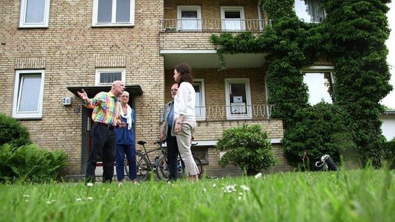 Anwohner vor einem Mehrfamilienhaus.  