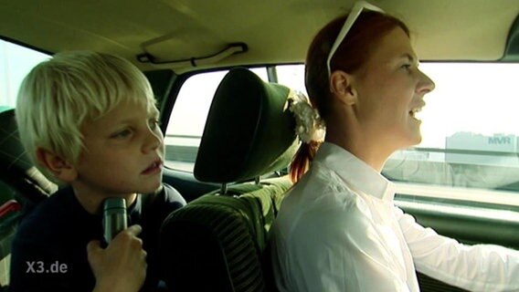 Ein Kind und eine junge Frau fahren im Auto  