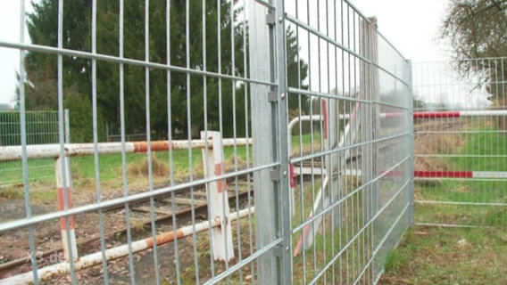 Ein Zaun verhindert das Betreten des Bahnübergangs.  