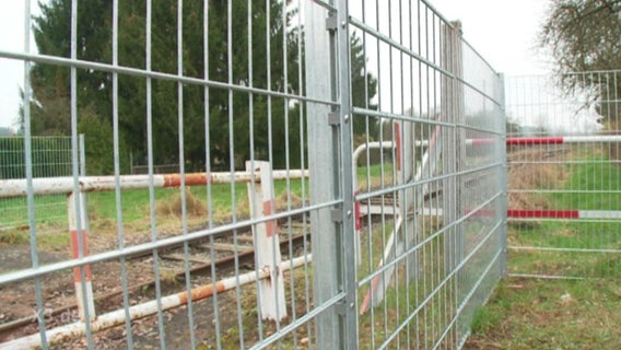 Ein Zaun verhindert das Betreten des Bahnübergangs.  