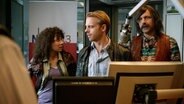 Drei Personen stehen in einem Radio- Studio.  