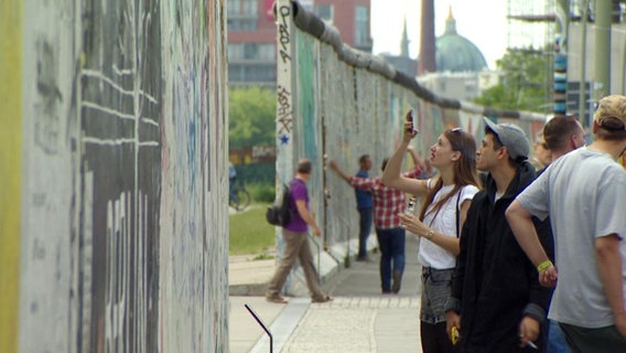 Menschen betrachten Überreste der Berliner Mauer  