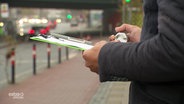 Vor der Brücke in Bremen jemand hält ein Schreibebrett mit Zahlenticker in der Hand.  