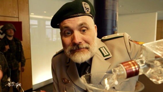 Ein Mann mit einer Bundeswehruniform füllt Schnaps in ein Glas  