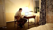 Ein Mann sitzt vor einem Computer.  