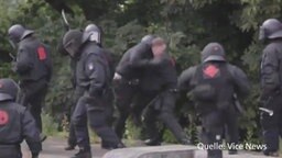 Ein Polizist schlägt auf einen Demonstranten ein.  