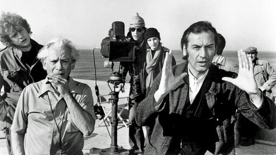 Regisseur Friedrich Munroe (Patrick Bauchau, r.), Kameramann (Sam Fuller, l.) sowie Teile der Crew beim Dreh des postapokalyptischen Science-Fiction-Films "The Survivors". © rbb/Wim Wenders Stiftung 