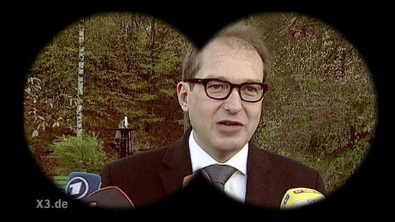 Dobrindt ist durch ein Fernglas zu sehen.  