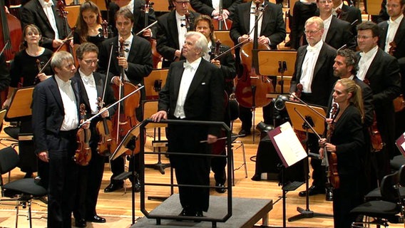 Christoph von Dohnányi und das NDR Sinfonieorchester stehen vor ihrem Publikum.  